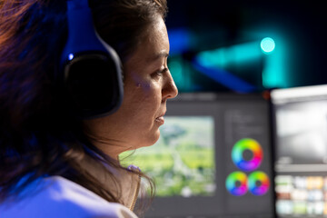 Poster - Videographer in media agency wearing headphones, ready to start color correcting raw footage, close up. Video editor editing video renders, using software to make montage from clips, listening music