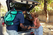 © DC Studio - Sweet couple in love preparing the car trunk for a summer holiday with luggage, feeling happy about their romantic getaway. Cheerful black people shows excitement for adventure.