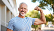 © ProSpace - Strong, healthy older man showing off bicep muscles with a happy expression, embracing fitness and an active lifestyle.