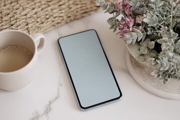 Poster - Modern smartphone with blank screen placed on marble surface next to coffee mug and decorative plant in cozy home setting