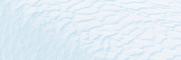 Wall Mural - Wide panoramic winter background with snowy ground. Natural snow texture. Wind sculpted patterns on snow surface.