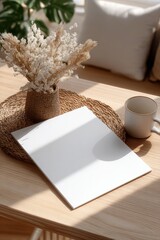Poster - Stylish modern workspace with blank notepad and coffee mug on wooden desk with decorative dried flower arrangement and cushions for comfort