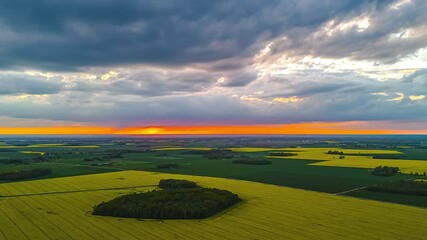 Wall Mural - sunset and moving clouds over yellow rapeseed fields in drone hyperlapse