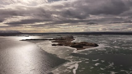 Wall Mural - Dramatic sunset behind clouds over an ice-covered lake. Iceland in all its glory from a drone