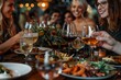© Azhorov - Four happy women in their 20s and 30s celebrate at a cozy restaurant dinner party. They enjoy wine glasses filled with red wine and delicious seafood appetizers, creating a warm and joyful atmosphere.