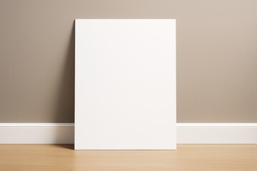 Poster - Blank white poster leaning on beige wall above wooden floor with soft lighting and clean background for creative branding or design concept mockup.