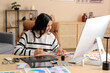 © Pixel-Shot - Young female graphic designer working with tablet and color palettes at table in office