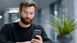 © pkproject - A business man using a smartphone in an office setting.