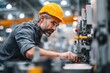 © ttonaorh - Professional worker in a hard hat working with a modern machine on a factory production line.