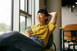© Westend61 - Woman relaxing with smartphone in modern office setting
