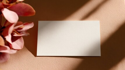 Poster - Blank card resting on a soft surface with pink flowers and gentle shadows in the background