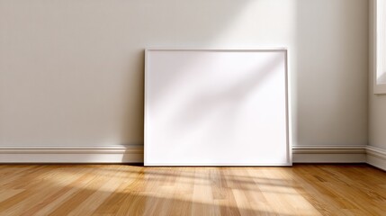 Poster - Blank white canvas leaning against a sunlit wall in a minimalist room with wooden floors