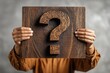 © Sinematicstd - Hands hold a wooden sign with a question mark