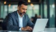 © WisChi - Concentrated Businessman Working on Laptop in Modern Office Setting