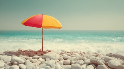 Aufkleber - Colorful beach umbrella on rocky shore with peaceful ocean background and cloudy sky.