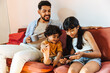 © (JLco) Julia Amaral - Latino family spending quality time on a couch with a digital device