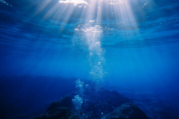 Wall Mural - an underwater photograph capturing sun rays streaming through deep blue ocean waters