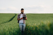 © standret - In checkered shirt, with digital tablet, walking. Man farmer is on the agricultural field