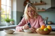 © Vadym - Middle-aged woman checks glucose levels in morning kitchen. Blonde female measures blood sugar with glucose meter near cereals and fruits. Diabetes management, health care, wellness.