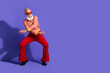 © deagreez - Happy man dancing in retro outfit with vintage elegance against a purple background celebrating trendy fashion