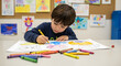 © reinh.art - Young Child Coloring with Crayons in Classroom