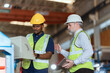 © 2B - Workers discuss project details in industrial facility during daylight hours with safety gear on