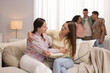 © New Africa - Friends hugging on sofa indoors, selective focus