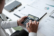 © mojo_cp - Office administrator reviewing audit documents on table with calculator and financial file folders