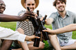 © Xavier Lorenzo - Diverse friends cheering with beer bottles while enjoying summer picnic at city park