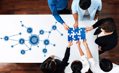 Fototapete - A diverse group of professionals collaborates on a project strategy, assembling puzzle pieces while analyzing visual data in a modern meeting room. Amity
