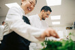 © Maskot - Low angle view of happy male chef preparing food while talking with female coworker at restaurant kitchen