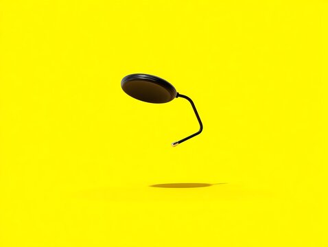 Black disc-shaped object, levitating, yellow background