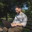 © Miljan Živković - Adult businessman sit on bench in a public park and use laptop