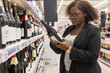 © Anna Berkut/Stocksy - woman choosing wine in supermarket grocery store shop
