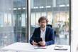 © Oleksii Syrotkin/Stocksy - CEO in business suit sitting at desk in office with tablet in hands