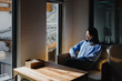 © Heng Yu/Stocksy - Woman Sitting by Window in Sunlight