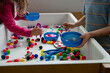 © Cara Dolan/Stocksy - Two preschool kids play with puff balls at a sensory table