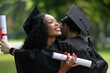 © ultramansk - Two graduates in gowns share a warm embrace, holding diplomas with smiles of joy and pride. The outdoor setting, with lush greenery, enhances this celebratory moment of achievement and friendship.