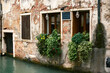 © Laura Stolfi/Stocksy - Falling plants grow out of windows facing narrow canal in Venice