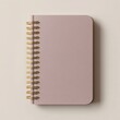© Andi - A mauve-colored spiral-bound notebook rests on a light background.