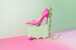 © Jelena Sijak/Stocksy - Bright pink high heel shoe on a stylish green pedestal with greenery