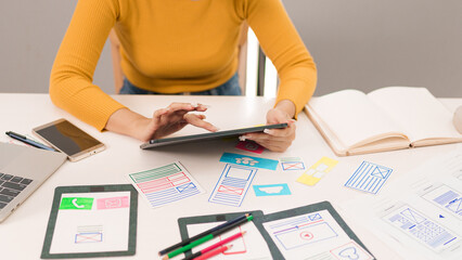 Wall Mural - adult asian woman ui designer working on tablet with user interface wireframes and sketches for mobi