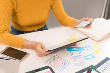 Canvas Print - asian adult woman ui designer creating interface designs on tablet for mobile app website developmen