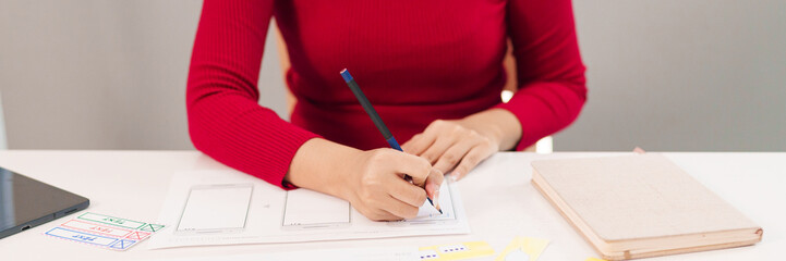 Canvas Print - ui ux designer creating mobile app interface design. asian woman sketching website wireframe layout 