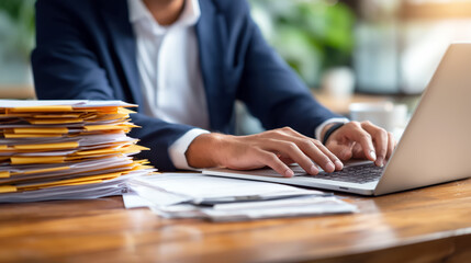 Poster - Business Professional Typing on Laptop at Office Desk Surrounded by Paperwork and Folders in Modern Workspace Environment