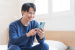 © polkadot - 寝室でスマホを使う男性