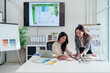© Pichsakul - Asian Interior Designers Collaboration on Color Palettes & Architectural Blueprints for Home Renovation Project in Modern Office Space with Laptop