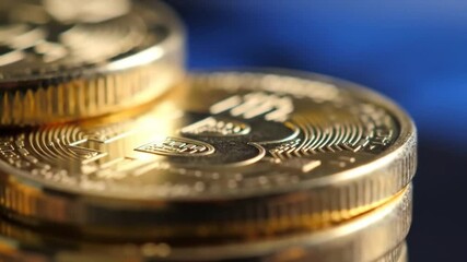 Poster - Close Up Stack of Golden Coins with Intricate Detailing on Reflective Surface Against Gradient Blue Background
