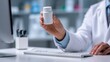 © Snowstudio - Medical professional doctor holding medication white bottle at computer desk