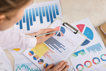 Fototapete - Woman with pen and business charts working at table in office, closeup